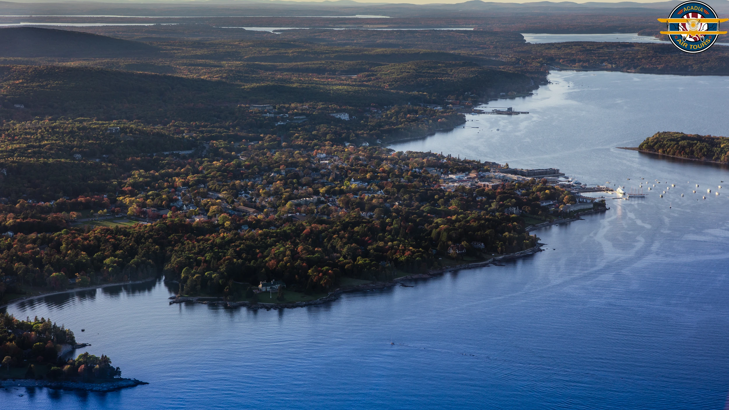Aerial view of Bar Harbor, Maine, surrounded by the waters of Frenchman Bay and fall-colored forests.