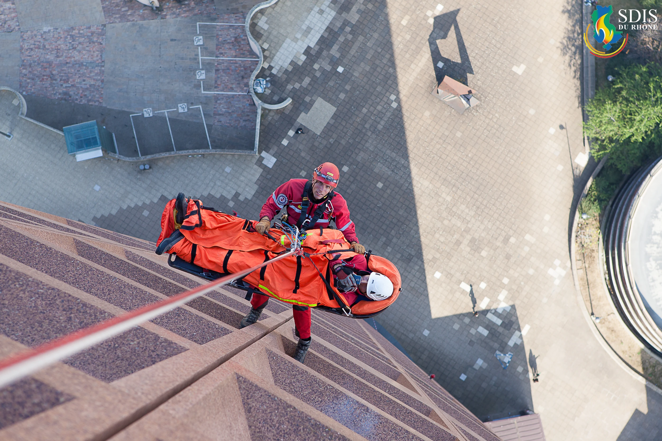 High-angle rescue training by SDIS du Rhône GRIMP unit on the Crédit Lyonnais Tower, descending with a stretcher.