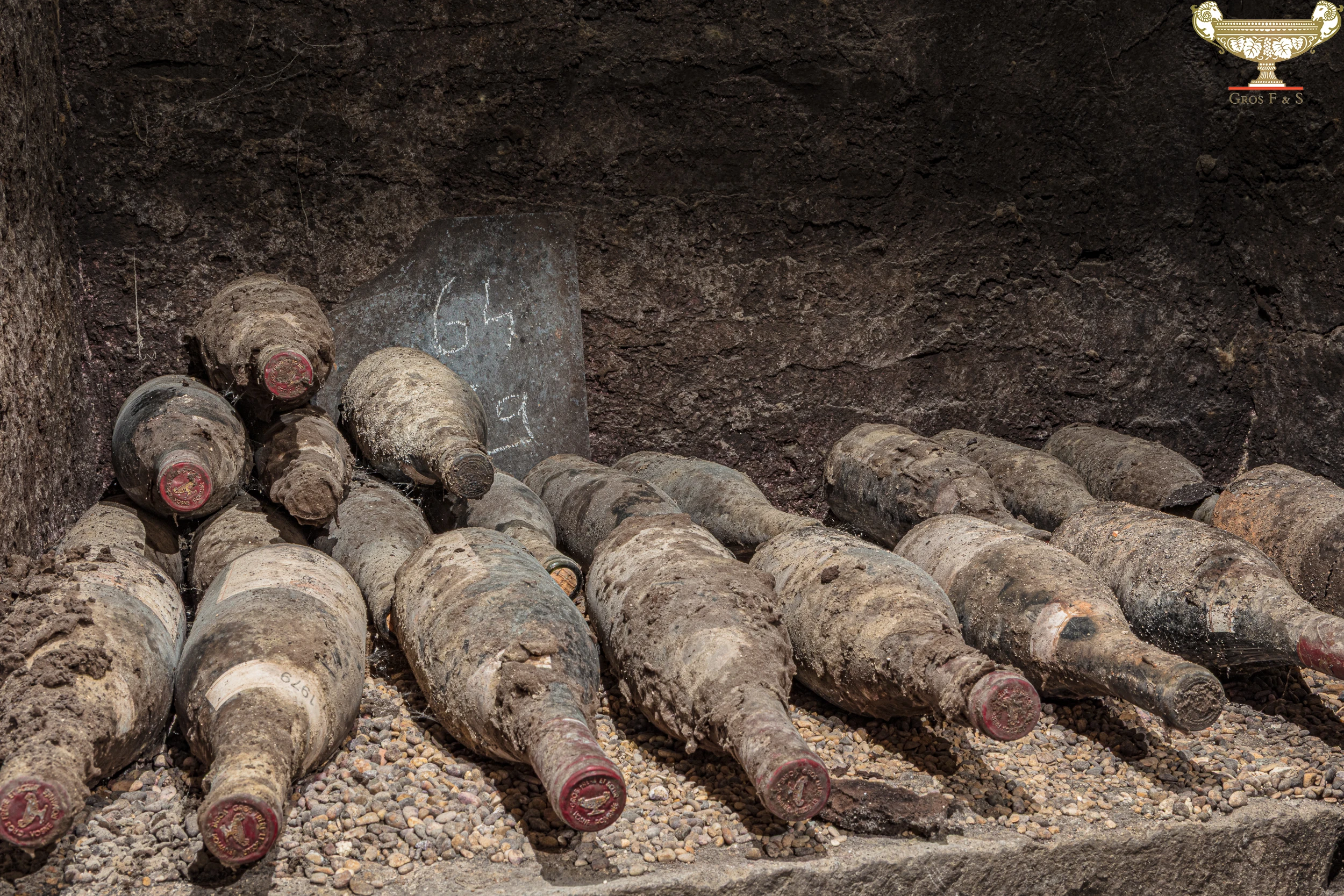 Old wine bottles covered in dust and mold in the historical cellar of Domaine Gros Frère et Sœur.