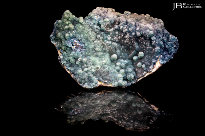 Botryoidal plumbogummite mineral specimen with blue-green tones from Yangshuo Mine, China, on black reflective vinyl surface.