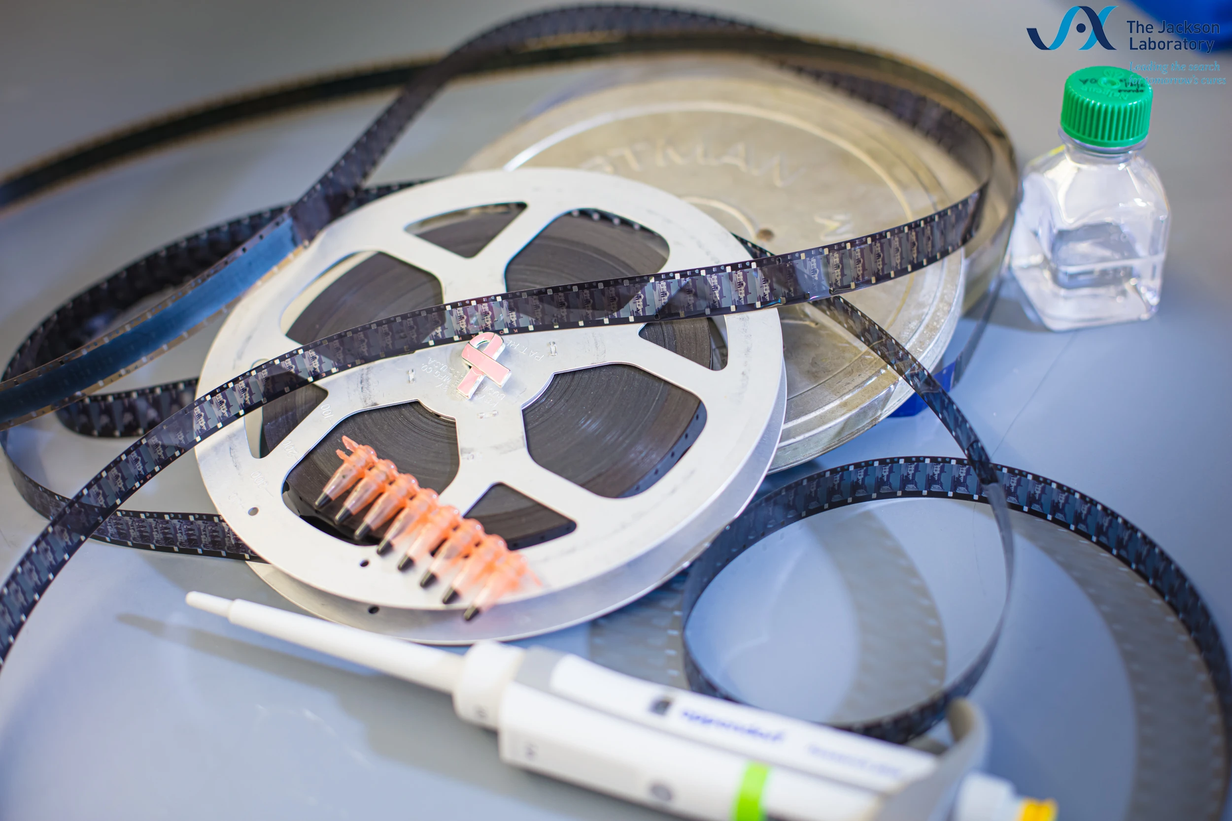 Metaphor of RNA splicing in scientific research using a film reel, pipette, and lab tools.