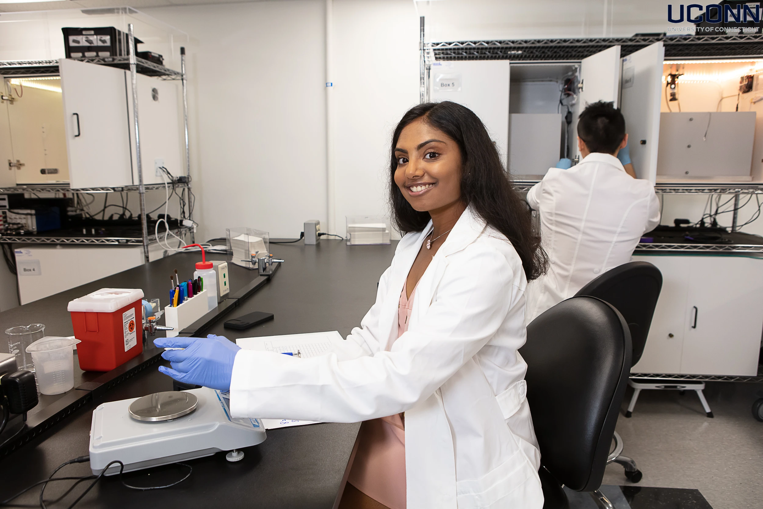 PhD student in a neuroscience laboratory at UConn using a digital scale and recording