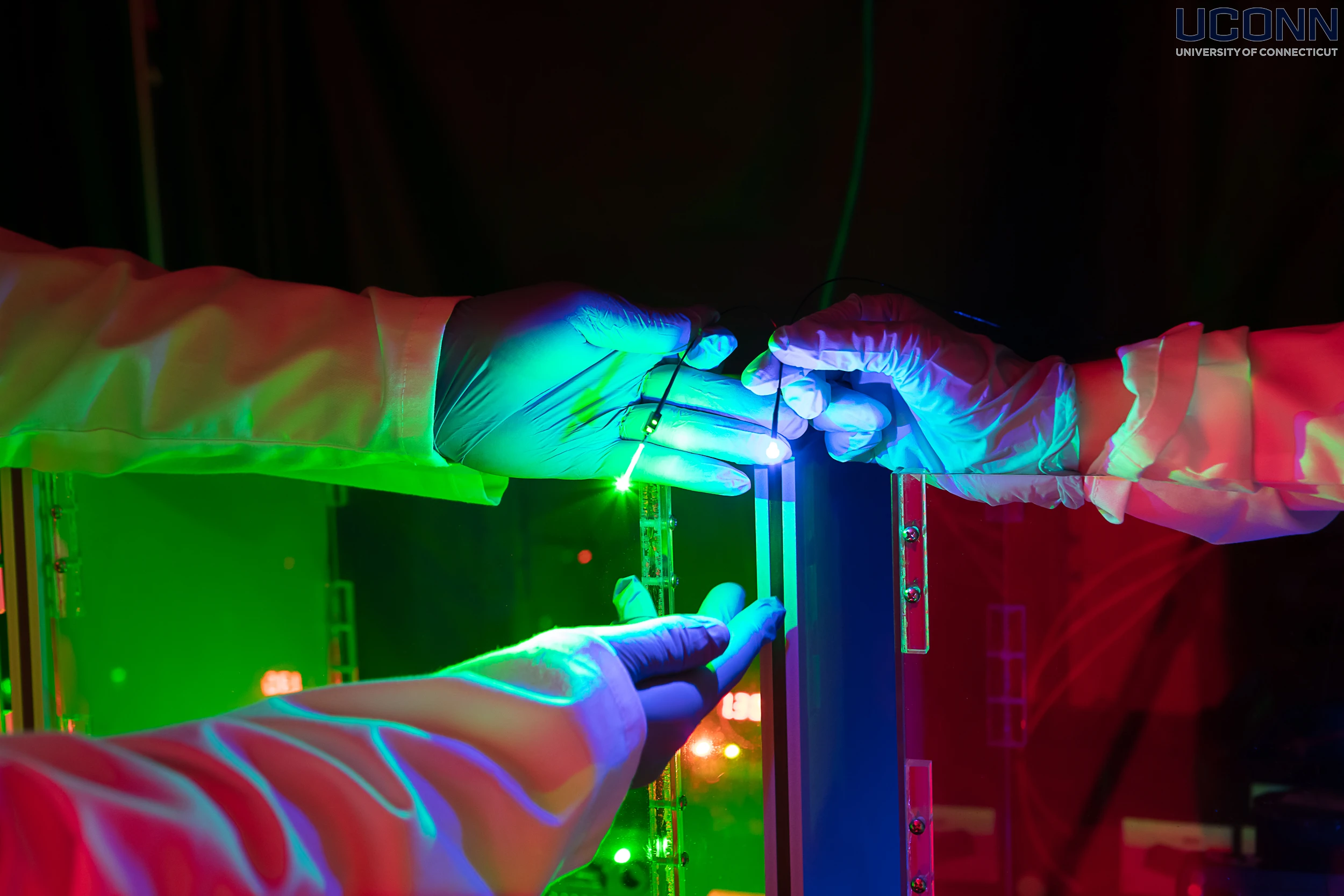 Close-up of UConn neuroscience researchers adjusting laser light inside a dark lab – 2022