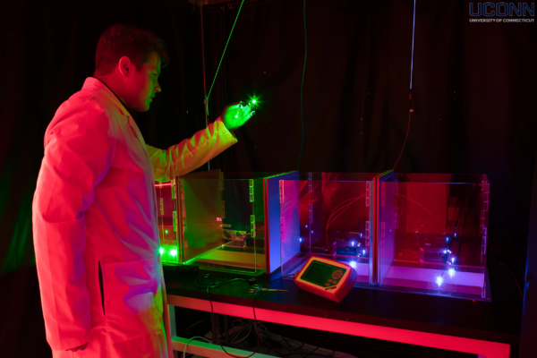 UConn – Graduate Student Using Laser Light for Neuroscience Research (2022) UConn neuroscience student using green laser in dark lab for neurological research – 2022