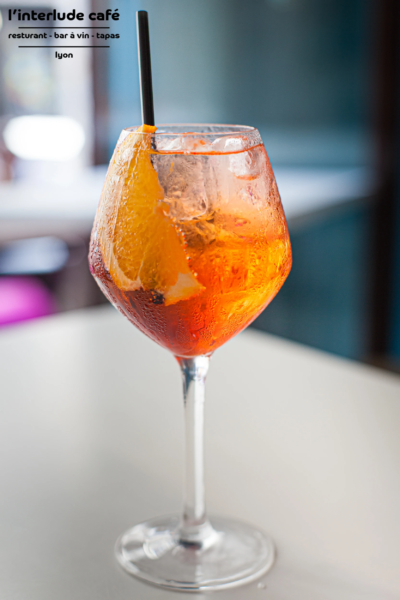 Aperol Spritz – Refreshing Cocktail at Interlude Café, Lyon Aperol Spritz cocktail with orange slice and straw at Interlude Café in Lyon