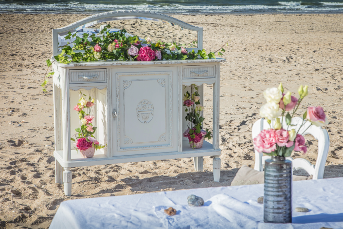 White patinated sideboard decorated with flowers on the beach – Atelier Gris Mousse “Imagine Your Home” campaign