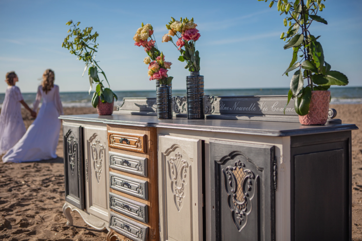 Hand-patinated buffet with floral decor and brides in background – creative visual identity for interior design