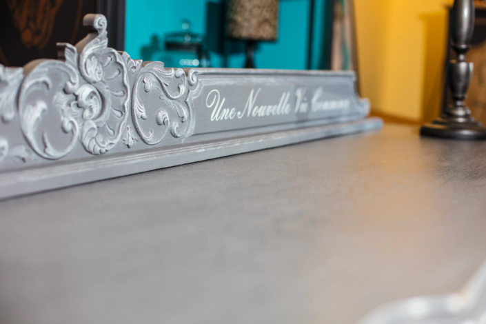 Ornate detail of a refinished dresser with carved flourishes and painted lettering – creative visual identity for interior design