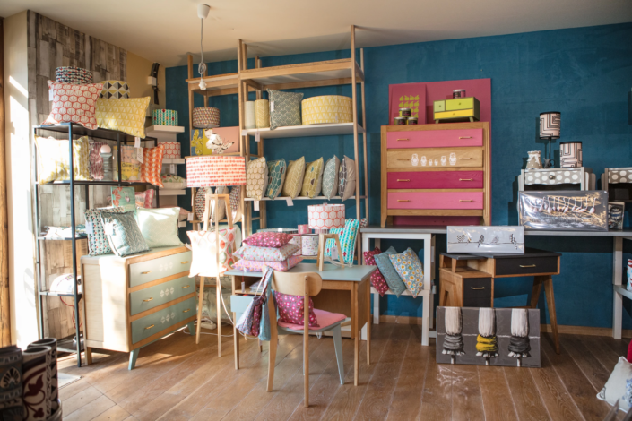 Colorful boutique display with printed cushions, painted furniture, and lamps – creative visual identity for interior design