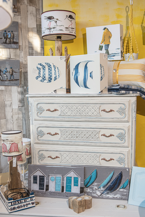 Patinated chest of drawers with coastal-themed decorations in boutique window – Atelier Gris Mousse
