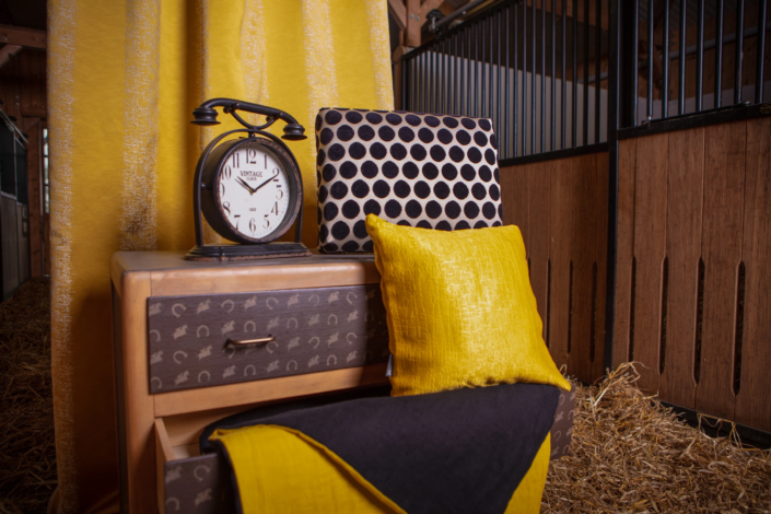 Interior styling with equestrian-themed dresser, yellow and black textiles, and vintage clock — creative visual identity for interior design by Atelier Gris Mousse.