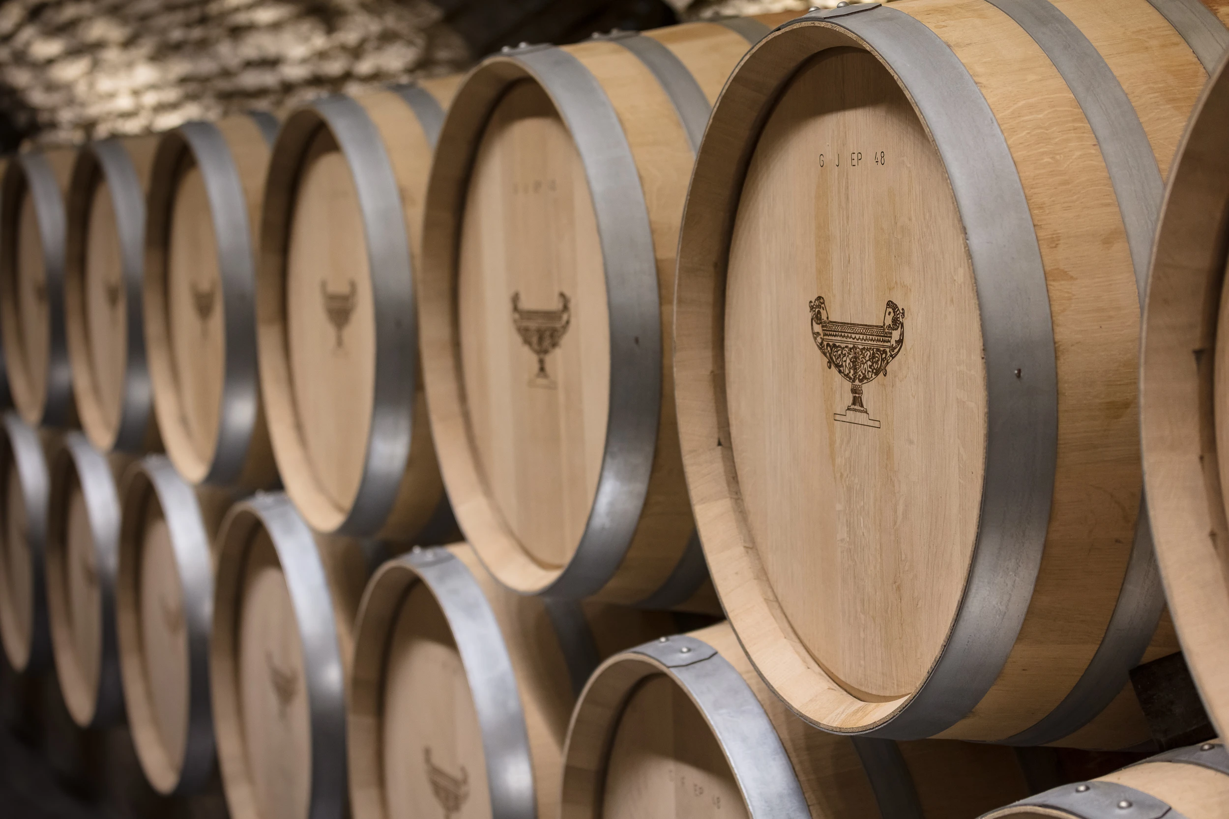 Close-up of oak wine barrels stacked in the vaulted cellar of Domaine Gros Frère et Sœur, Burgundy.