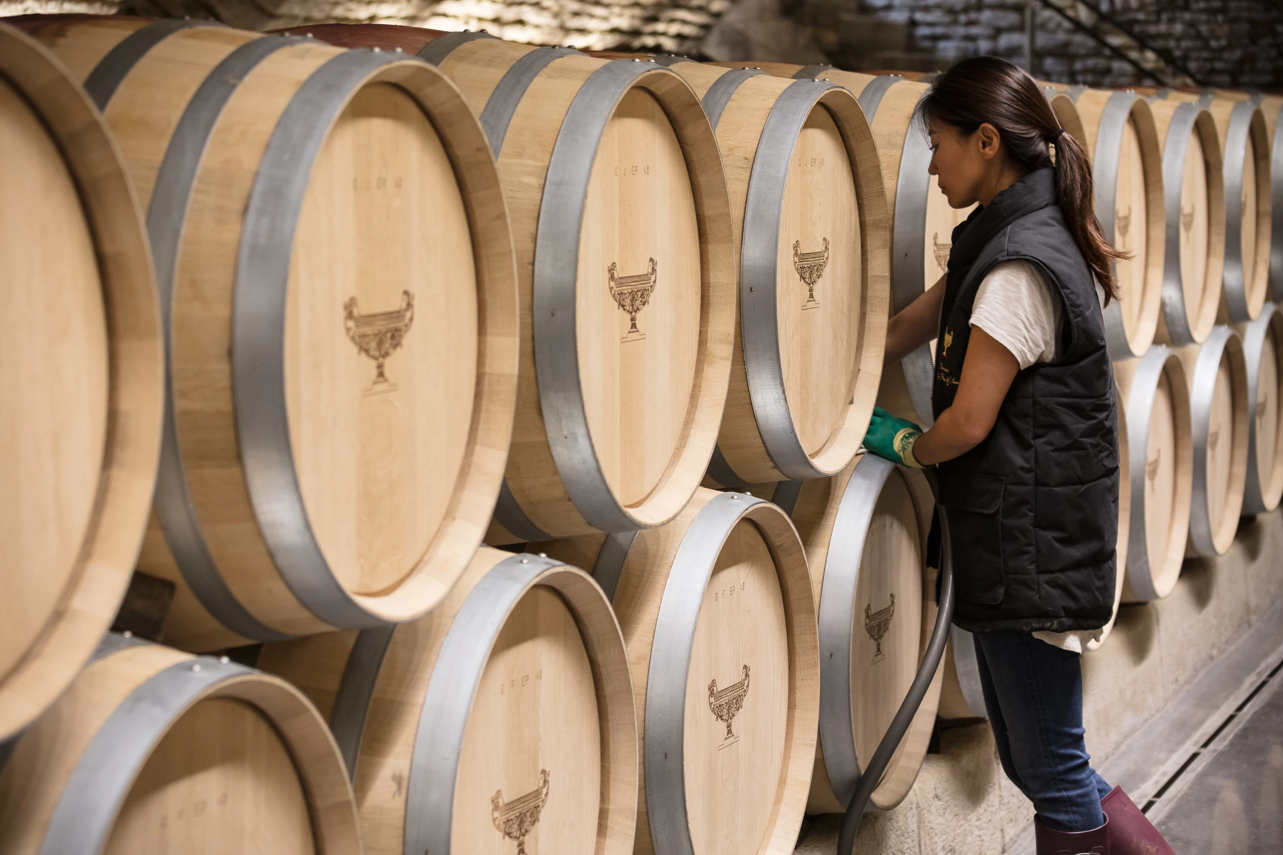 Winemaker managing oak barrels in the cellar of Domaine Gros Frère et Sœur in Burgundy.