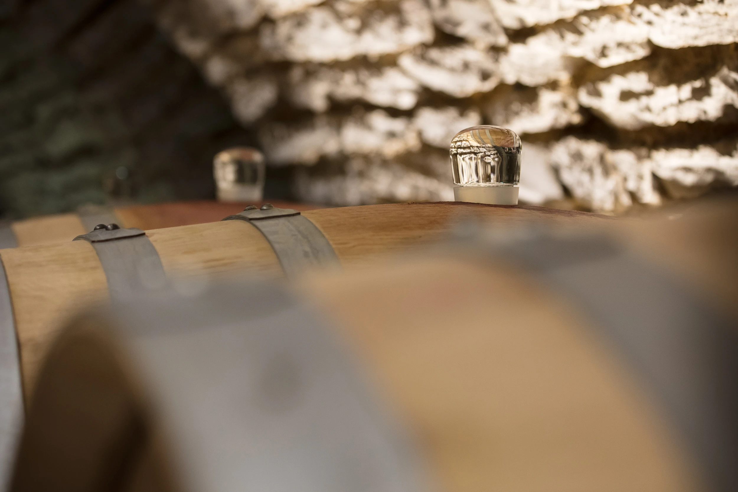 Close-up of a wine barrel with a glass fermentation airlock in the cellar of Domaine Gros Frère et Sœur.