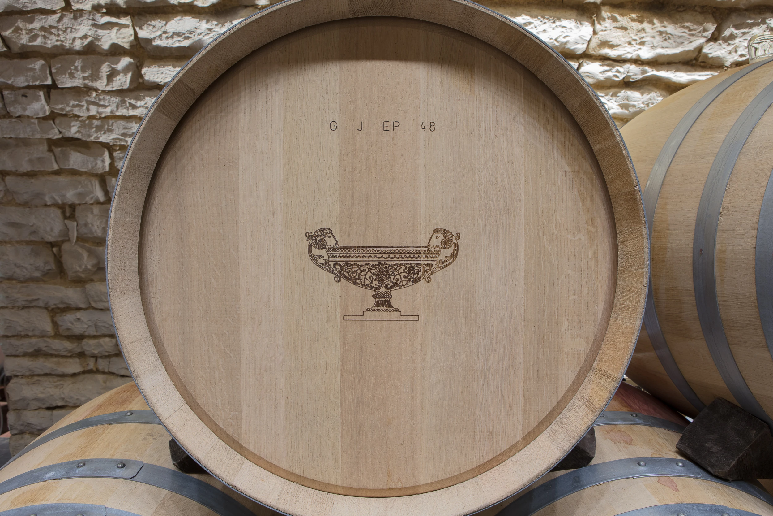 Close-up of an oak wine barrel engraved with the emblem of Domaine Gros Frère et Sœur.