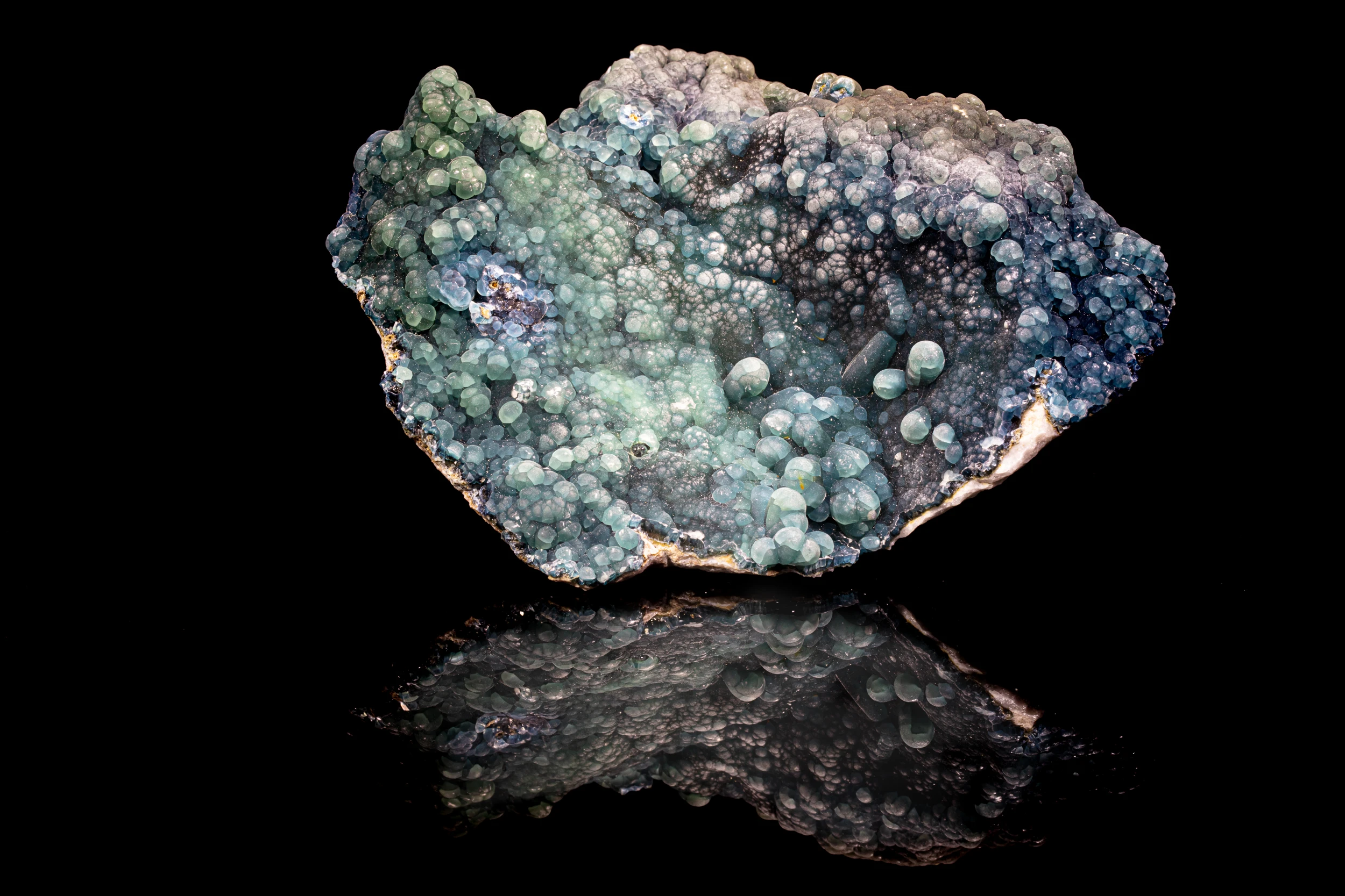 Botryoidal plumbogummite mineral specimen with blue-green tones from Yangshuo Mine, China, on black reflective vinyl surface.