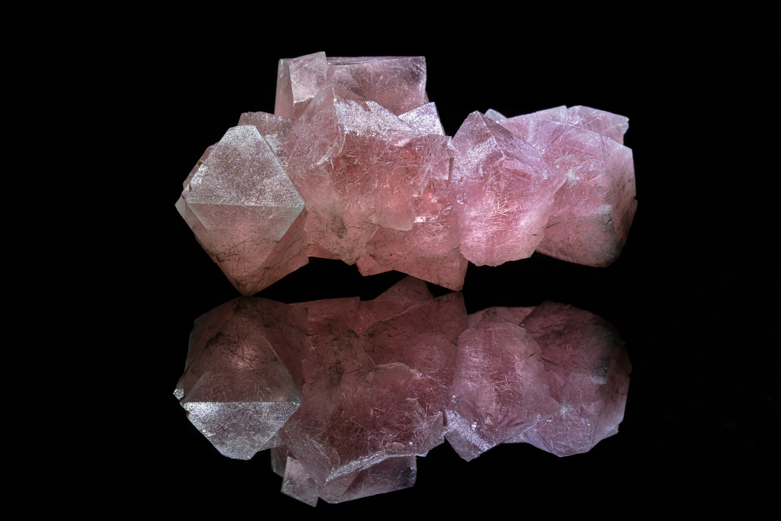 Pink fluorite crystal cluster from England, photographed on black vinyl for mirror reflection