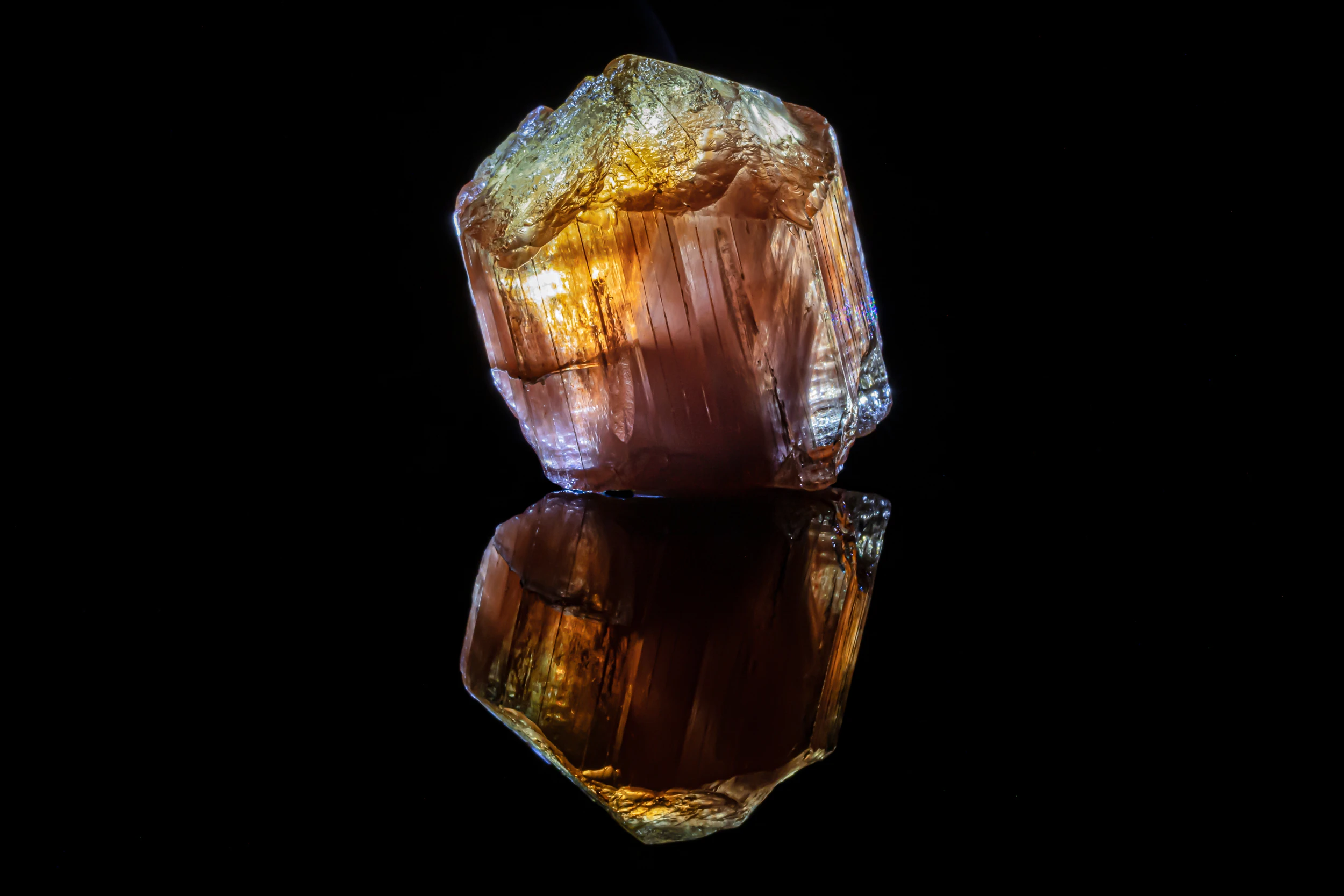 Golden scapolite crystal from Tanzania, photographed on black vinyl with reflective surface