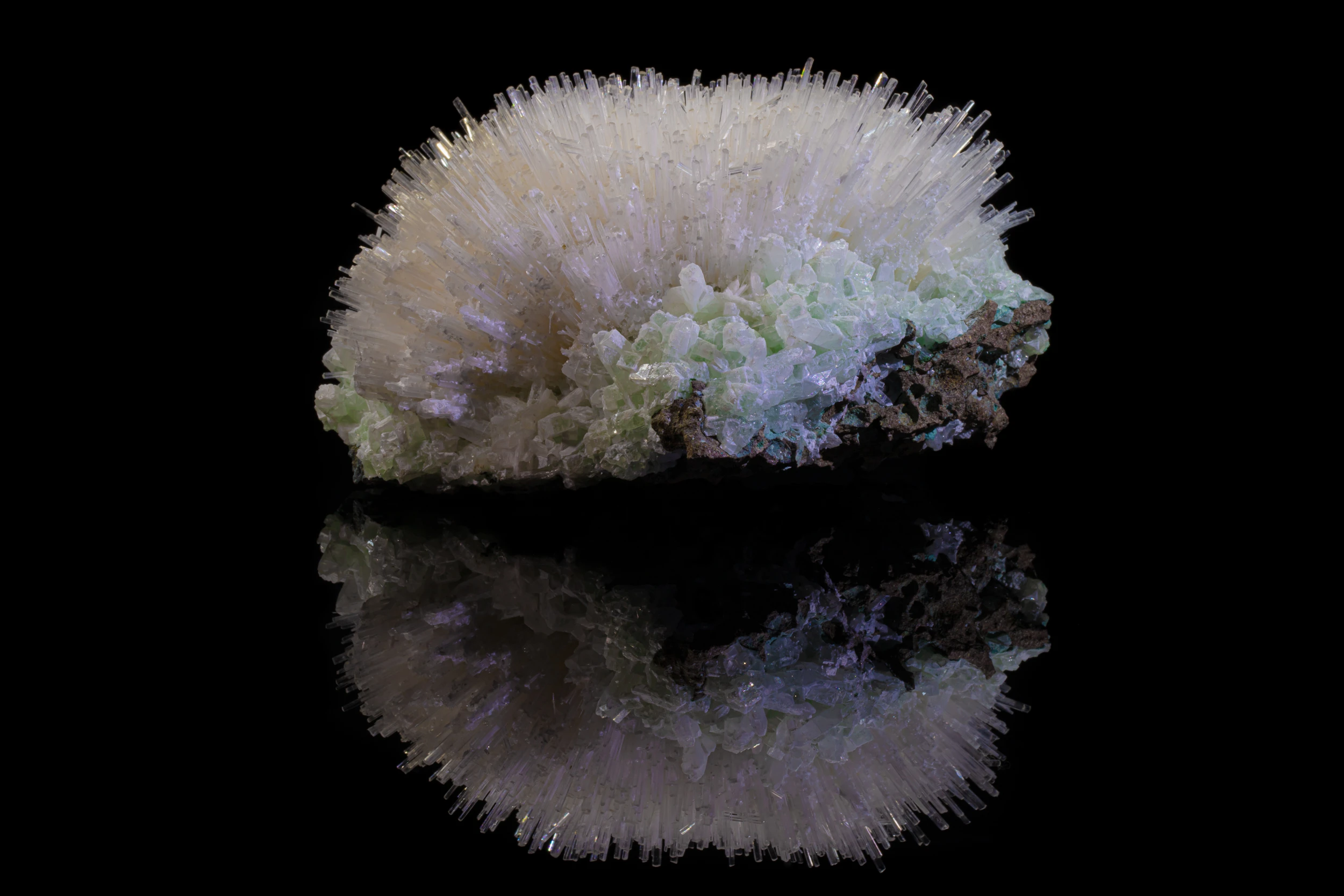 Mesolite spray atop apophyllite crystals with matrix, from Pune, India, captured with reflection on black vinyl background.