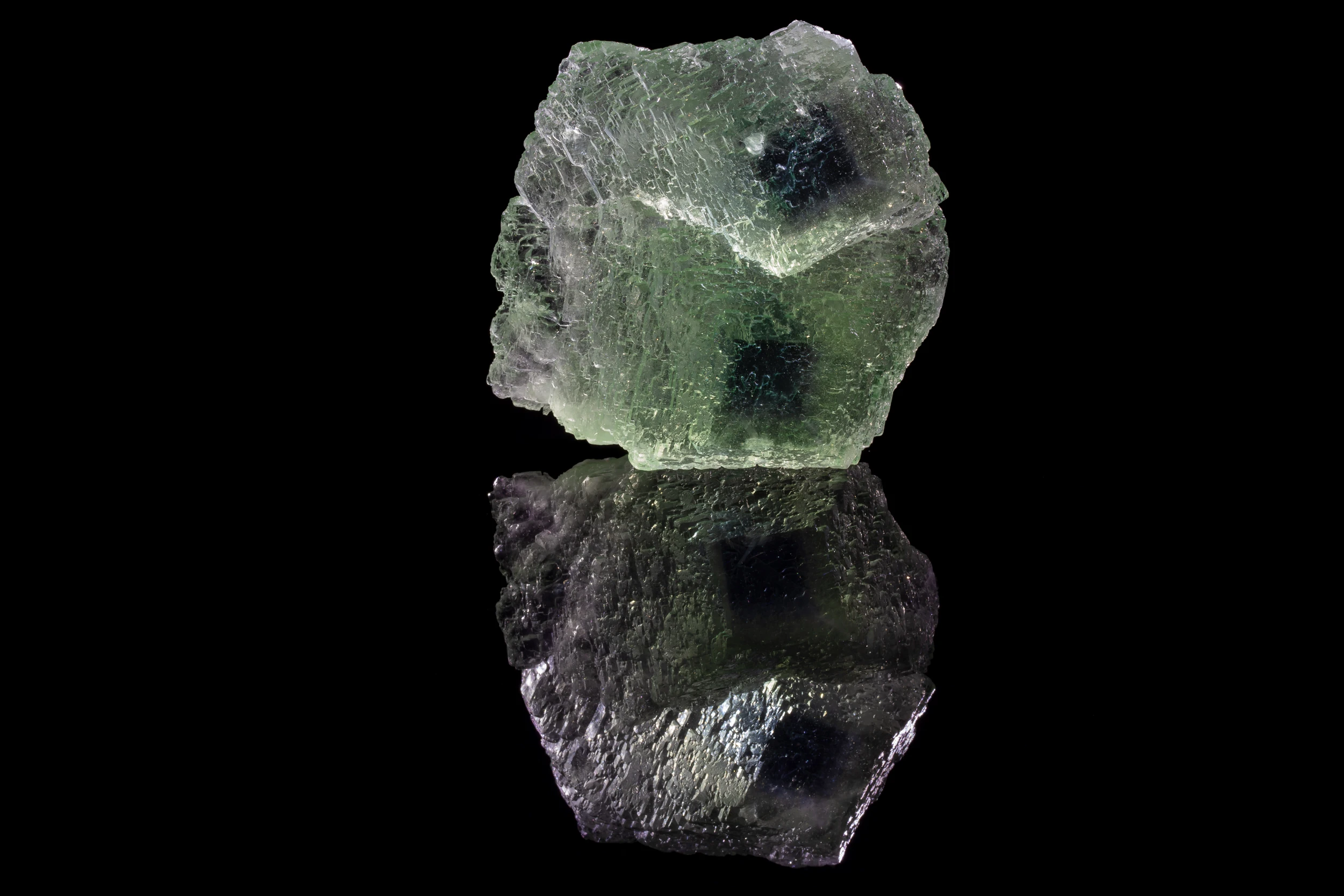 Chinese green fluorite crystal with deep phantoms – mineral photography on black vinyl surface (2022)