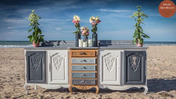 Restyled sideboard in grey, white and natural wood, lettered "Une Nouvelle Vie Commence", set with flowers and candles