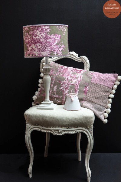 Patinated white chair with a mauve toile de Jouy lampshade and cushion, a small pink shade beside them