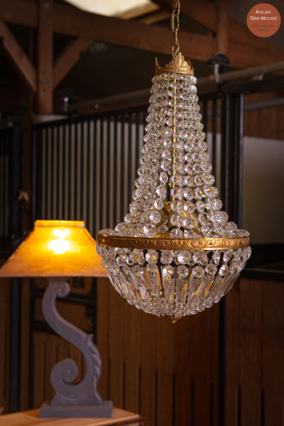 Crystal basket chandelier hanging in a stable beside a restyled table lamp with a lit amber shade