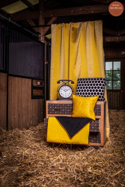 Restyled chest of drawers with a horseshoe-pattern finish, styled with yellow and polka-dot cushions and a vintage clock, on straw