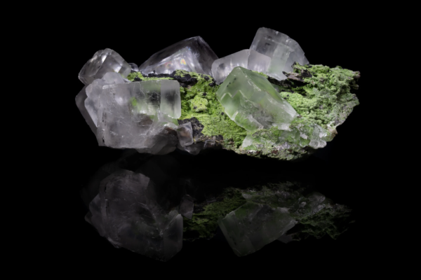 Colorless and pale green calcite crystals on a bright green mottramite crust, mirrored on black vinyl, Namibia