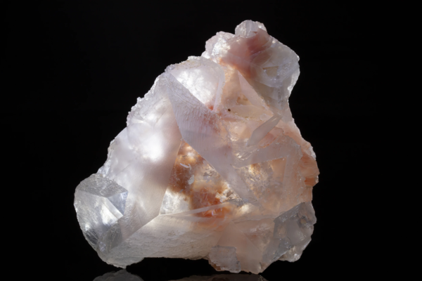 Pale pink and white dolomite crystals with a silky surface, lit so the light passes through the specimen, Brazil