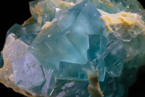 Blue-green fluorite, France Macro view of blue-green fluorite cubes with stepped faces and yellow crystalline crust in the gaps, France