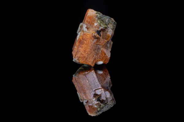 Orange serandite crystal with stepped faces and small white and black associated minerals, mirrored on black vinyl, Canada